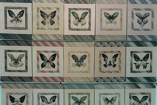 An installation view of textile art by Kate Geck called Reality Is an Interface. The printed and embroidered textiles are made using generative machine learning models, as is the large woven tapestry. This work is exhibited at Haus of Vovo Gallery in Tasmania, Australia.